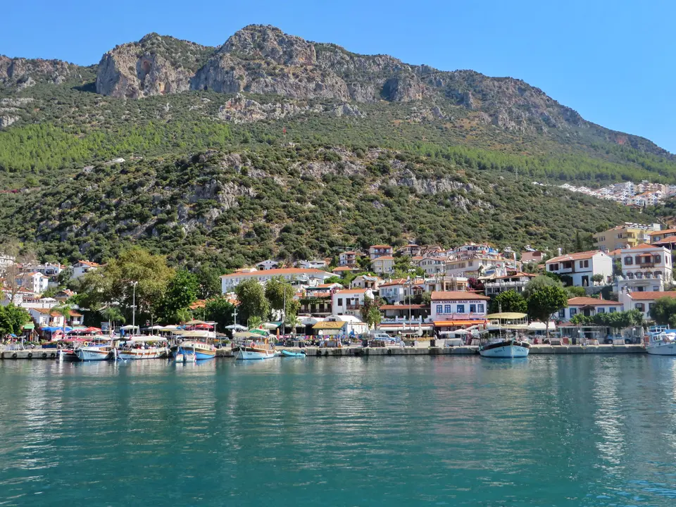 Kaş limanı: dağların eteğinde kasaba evleri ve sakin denizde tekneler